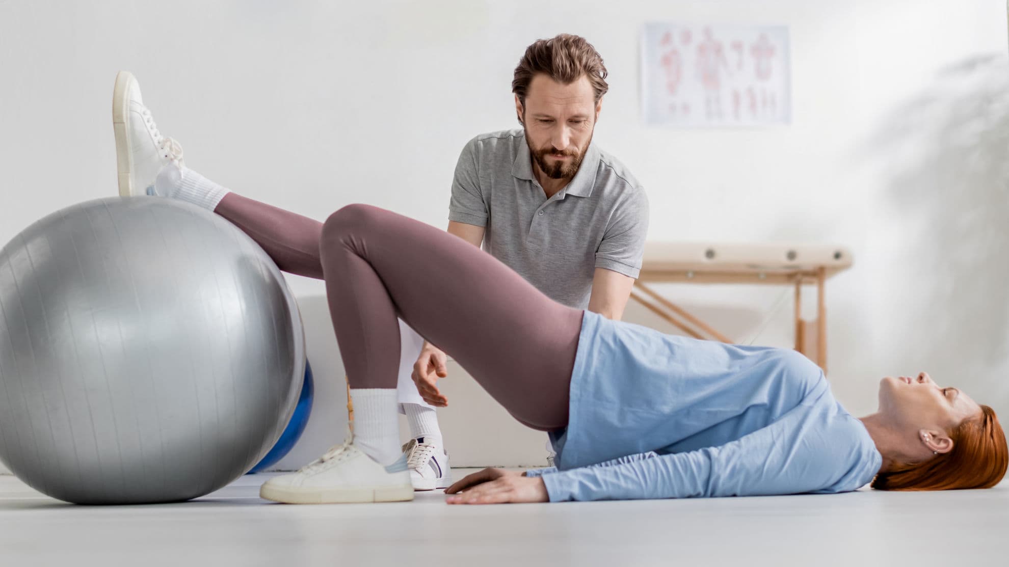 ATHERA Therapeutin führt Bobath-Behandlung an der Hüfte einer liegenden Patientin durch